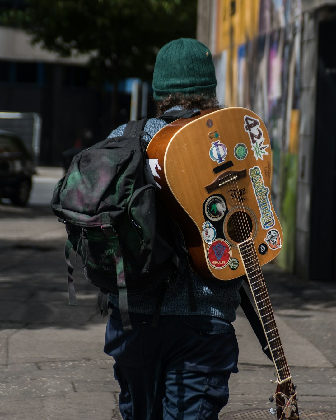 man in black jacket wearing brown acoustic guitar