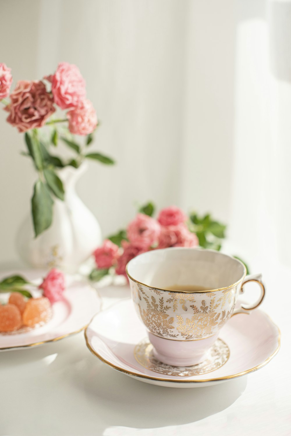 white and pink floral ceramic teacup on saucer