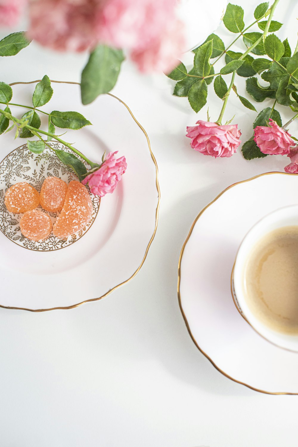 white ceramic cup with saucer beside pink flowers