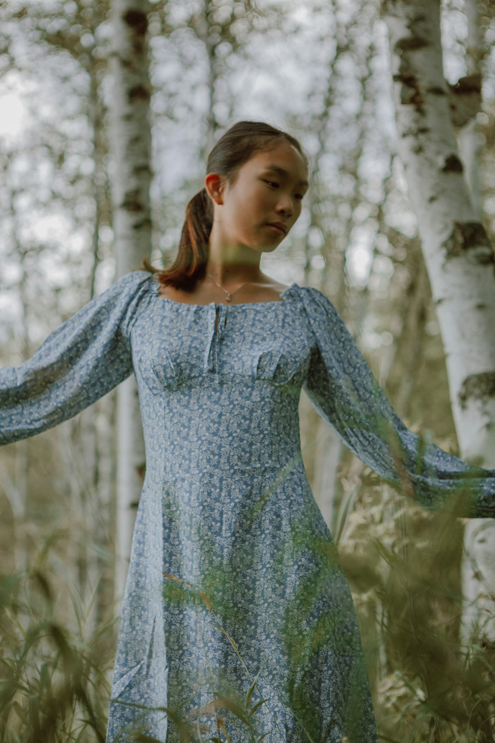 woman in green floral dress standing near green trees during daytime