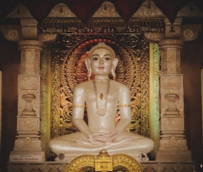 gold buddha figurine on gold and black floral textile