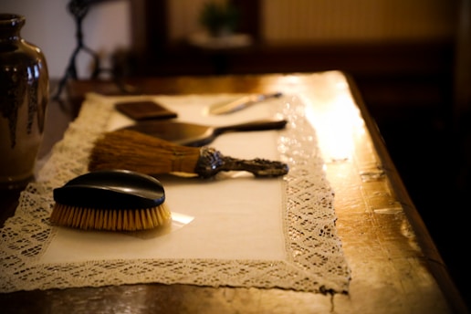 black and brown hair brush on white table cloth