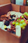 Happy customer receiving a neatly packed box of fresh healthy snacks at their doorstep.