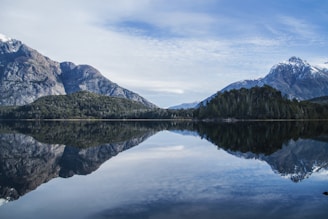 lake near mountain under cloudy sky during daytime