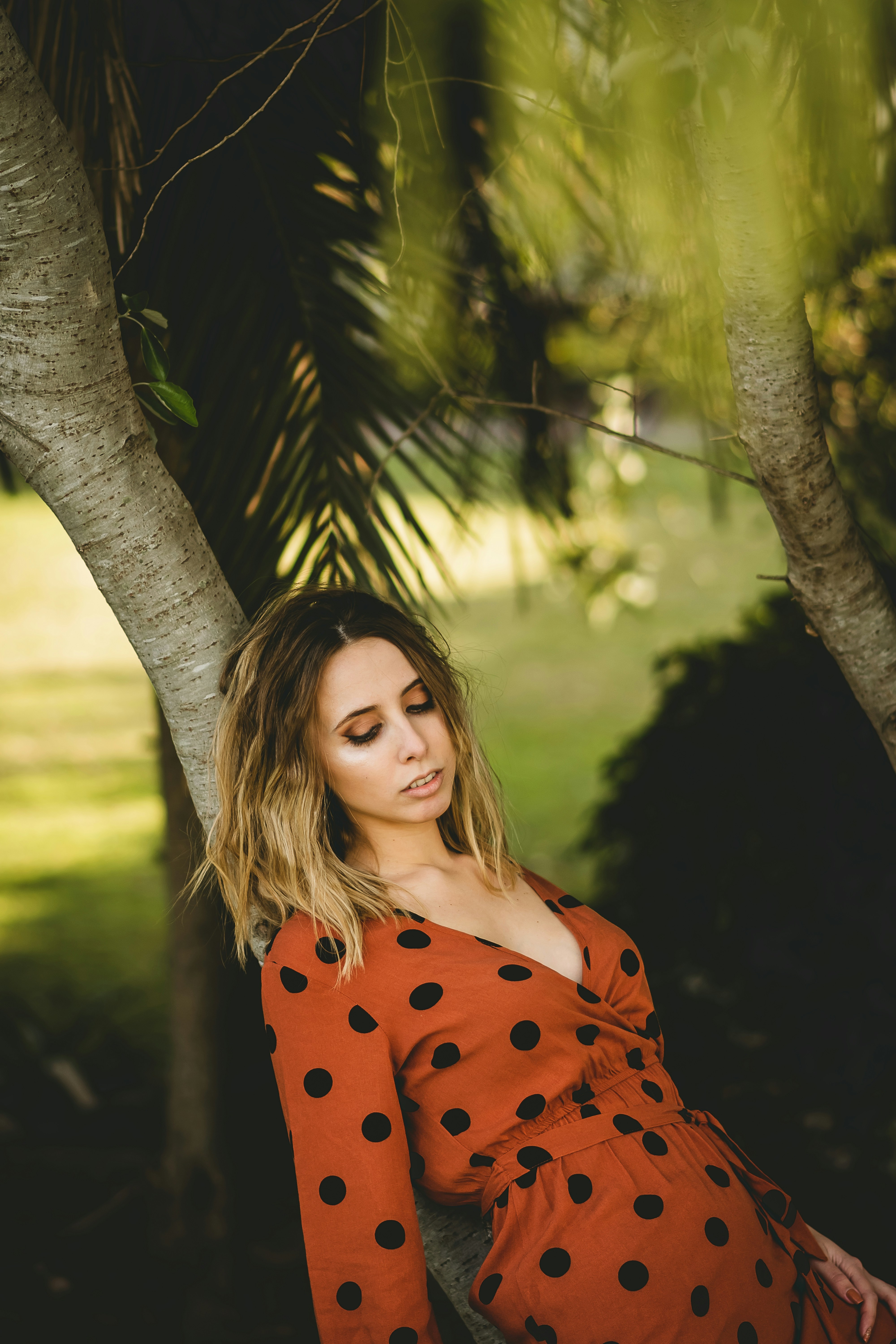 woman in red and black polka dot dress standing beside tree