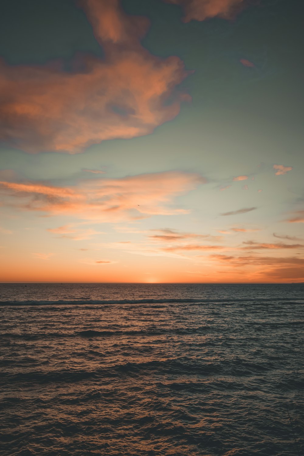 body of water under cloudy sky during sunset