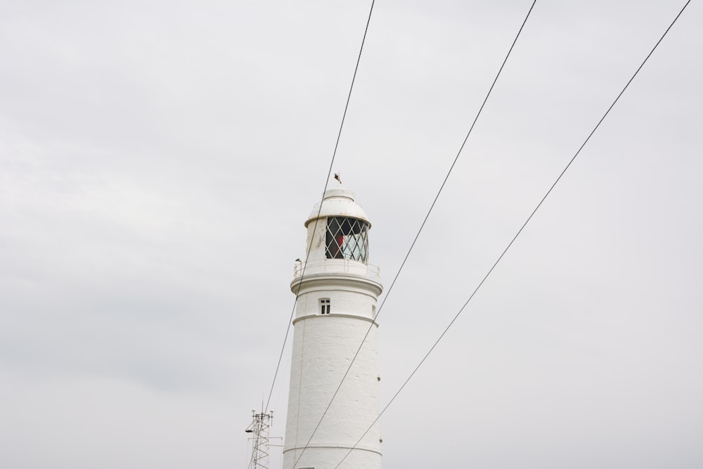 white and black lighthouse under white clouds during daytime