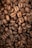 A close-up view of roasted coffee beans piled together, showcasing their rich brown color and various sizes. The beans have visible textures and natural grooves, indicating their quality and roast level.