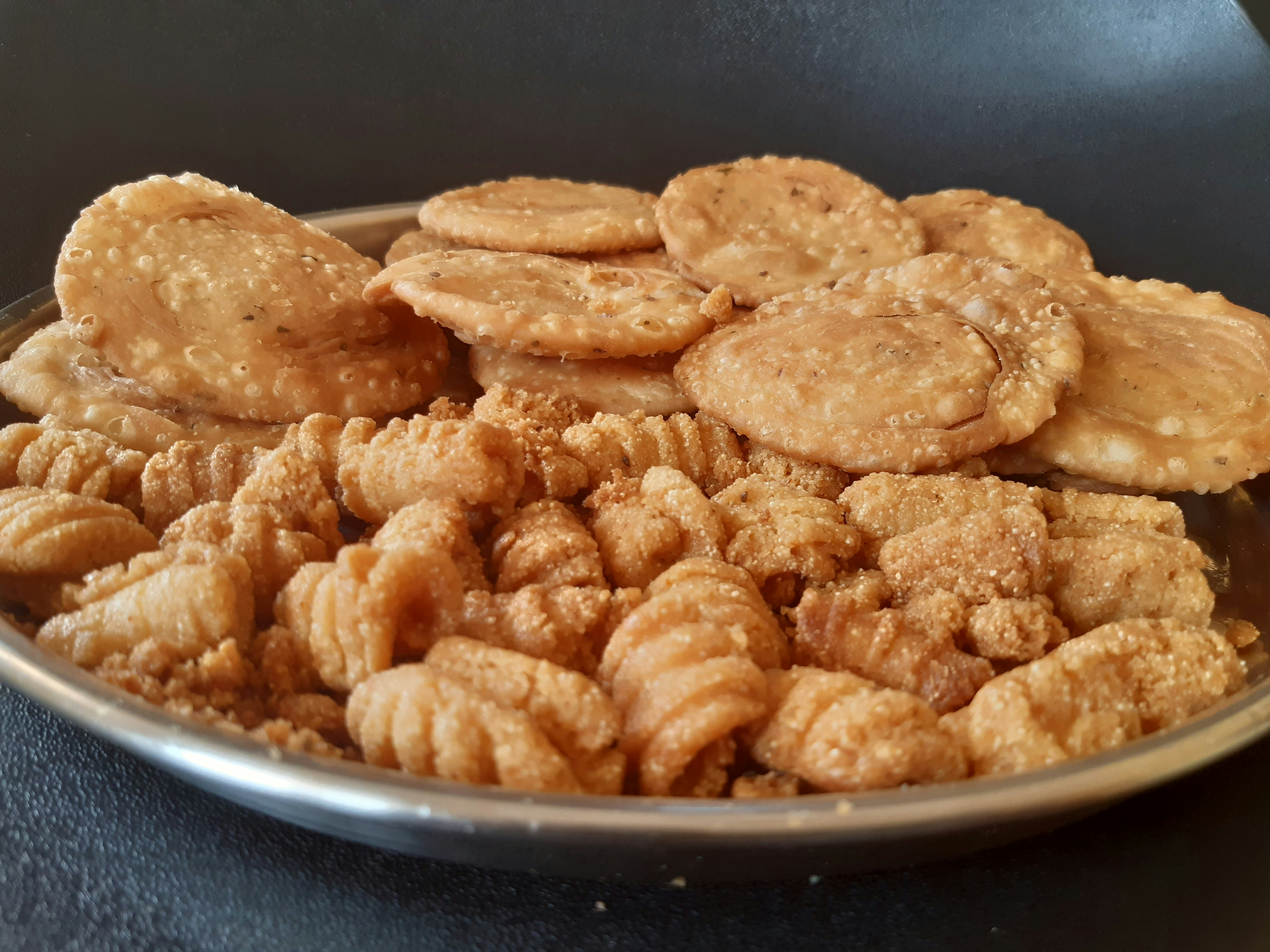 Assorted Indian snacks and namkeen in bowls with warm ambient lighting