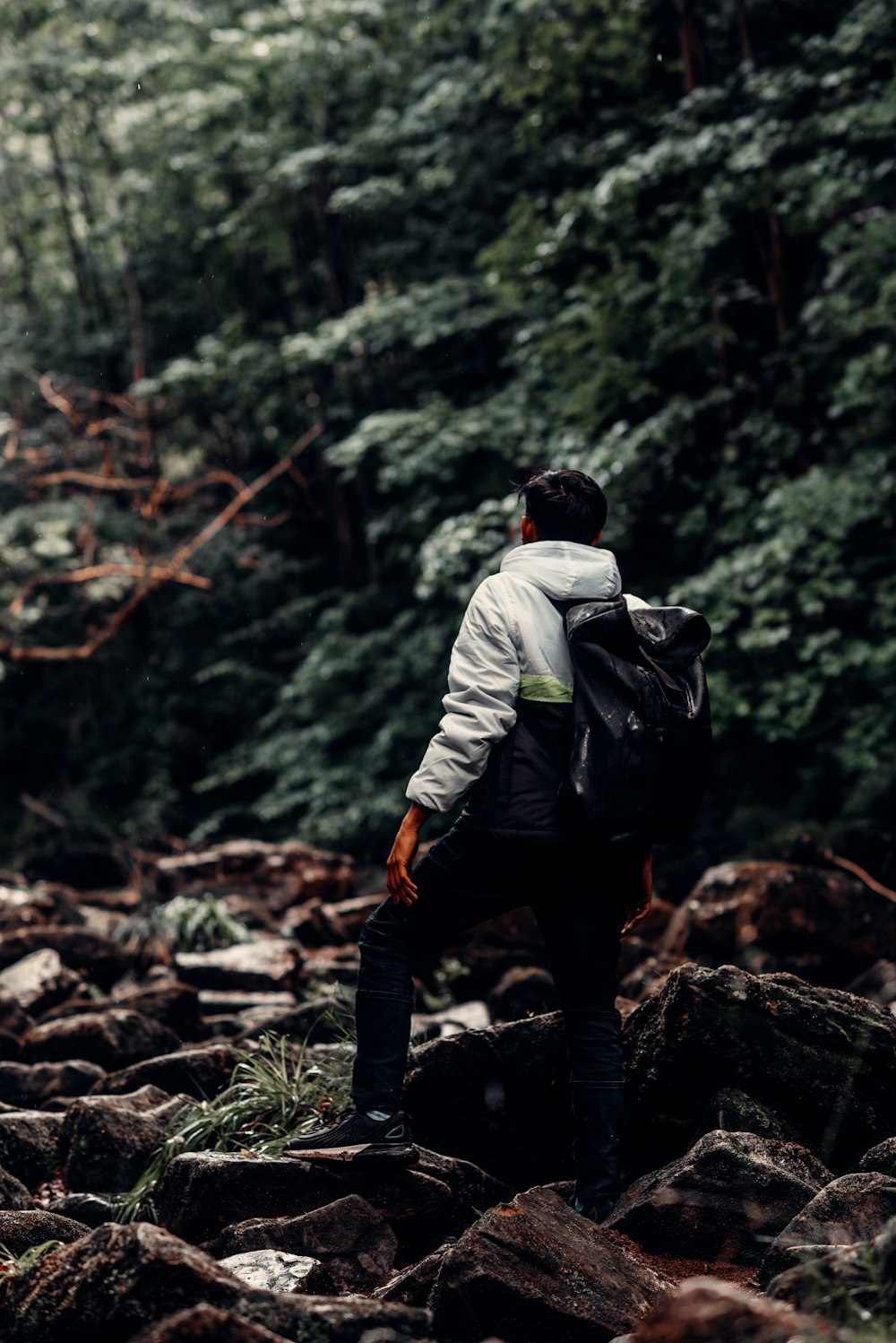 Homme en veste blanche et pantalon noir debout sur Brown Rock pendant la journée