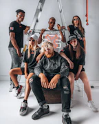 A diverse group of models confidently posing in bold streetwear pieces on an urban rooftop.