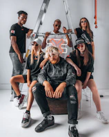 A group of fashion-forward individuals in oversized dark streetwear, standing confidently in an underground setting.