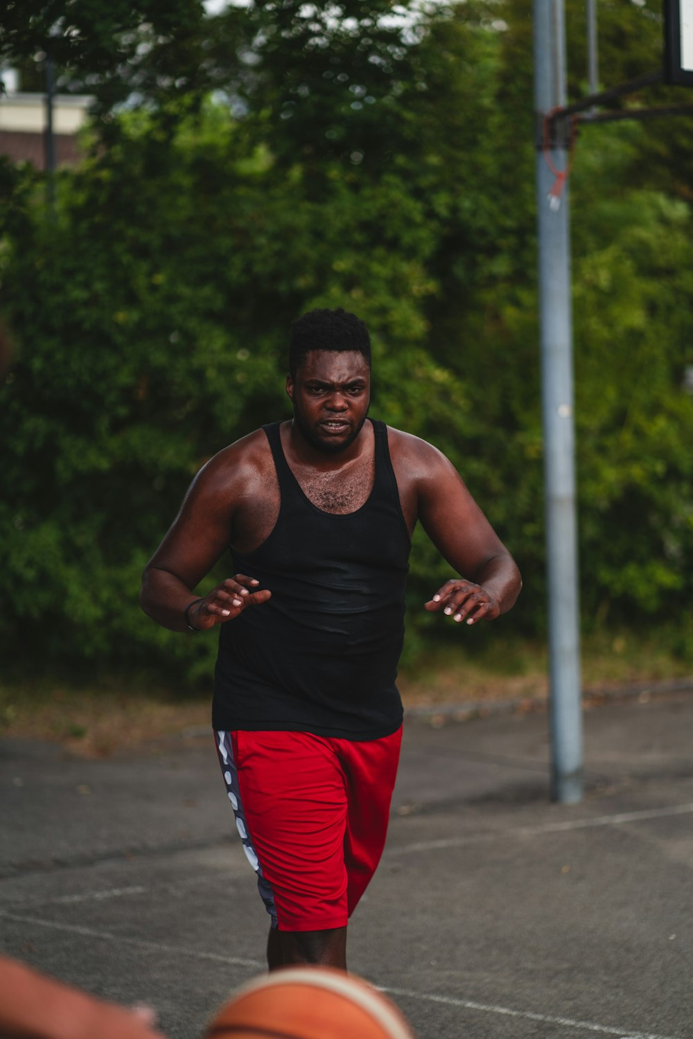 man in black tank top and red shorts running on road during daytime