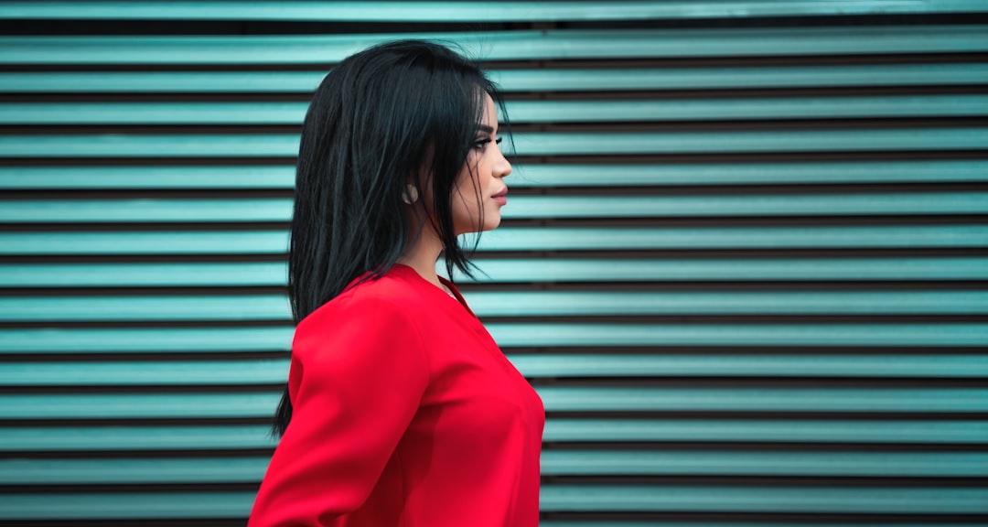 woman in red long sleeve shirt standing near gray roll up door