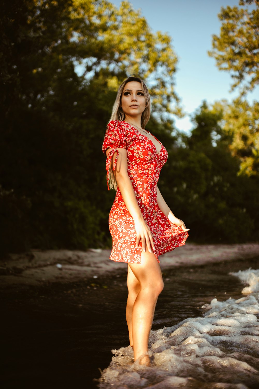 Mujer en vestido floral rojo y blanco de pie sobre el agua