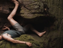 man in gray t-shirt and gray shorts sitting on rock