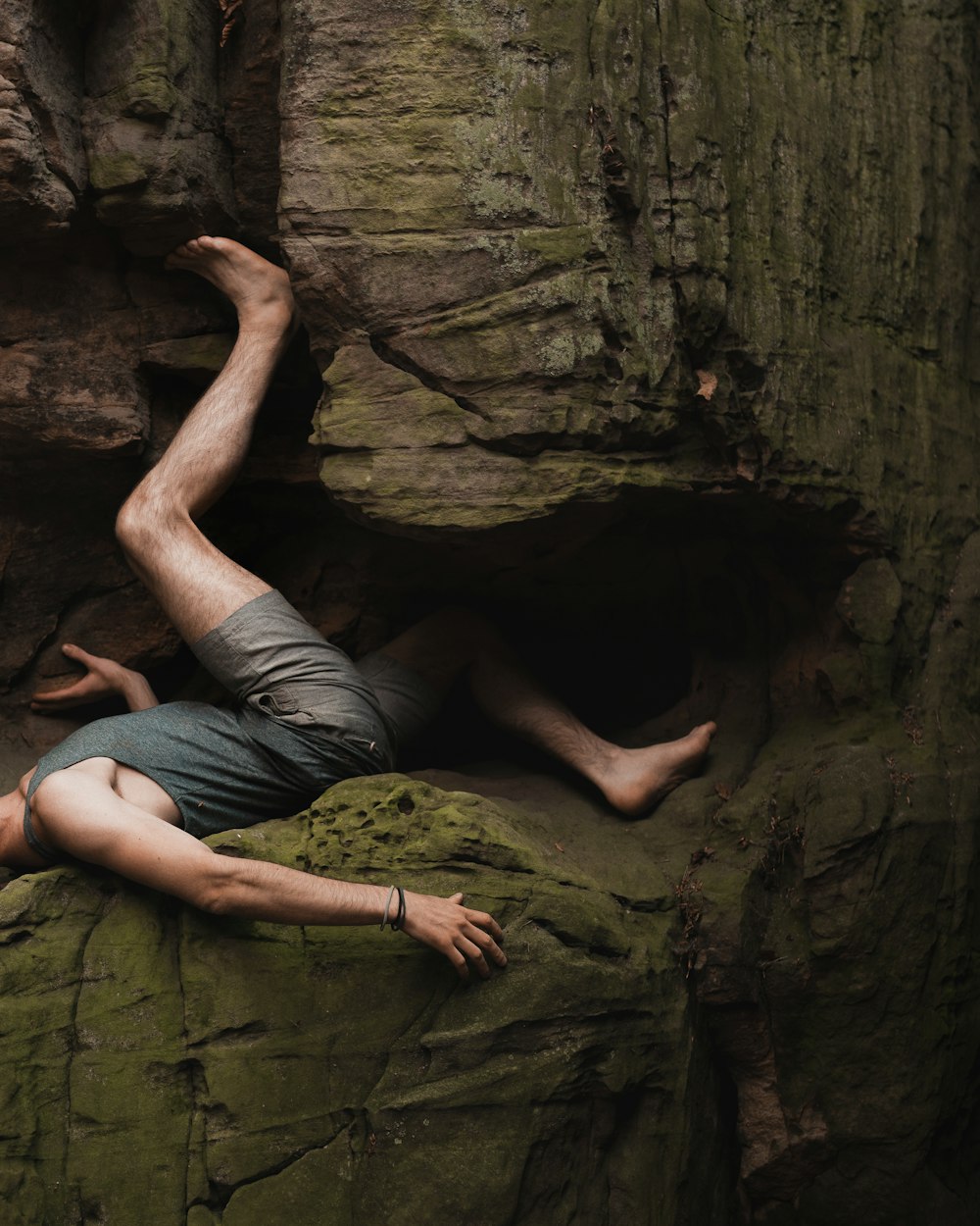 man in gray t-shirt and gray shorts sitting on rock