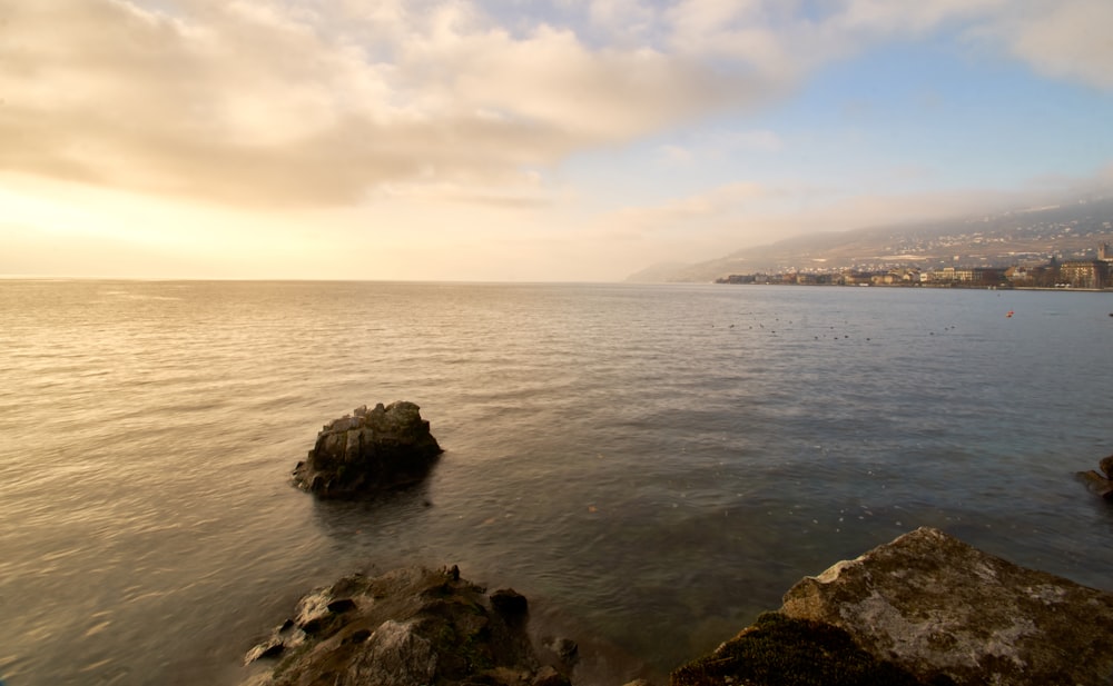 black rock formation on sea under white clouds during daytime