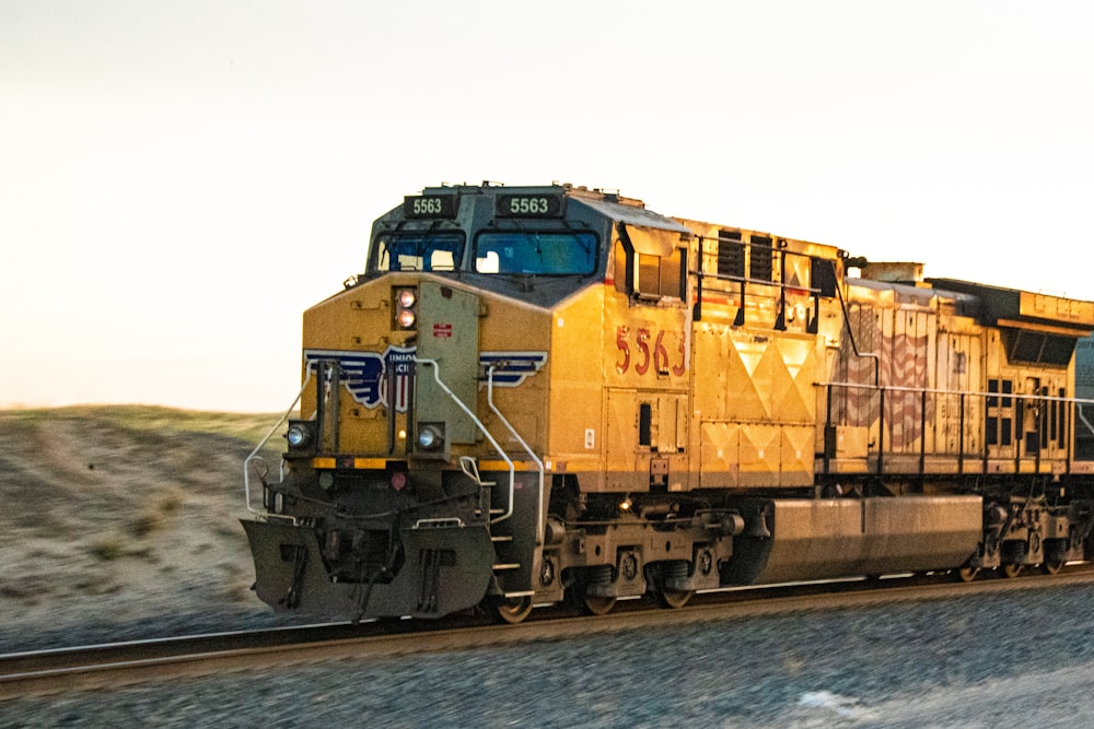 yellow and blue train on rail tracks on body of water during daytime