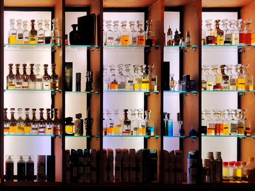 Rows of colorful glass perfume bottles resting on rustic wooden shelves.