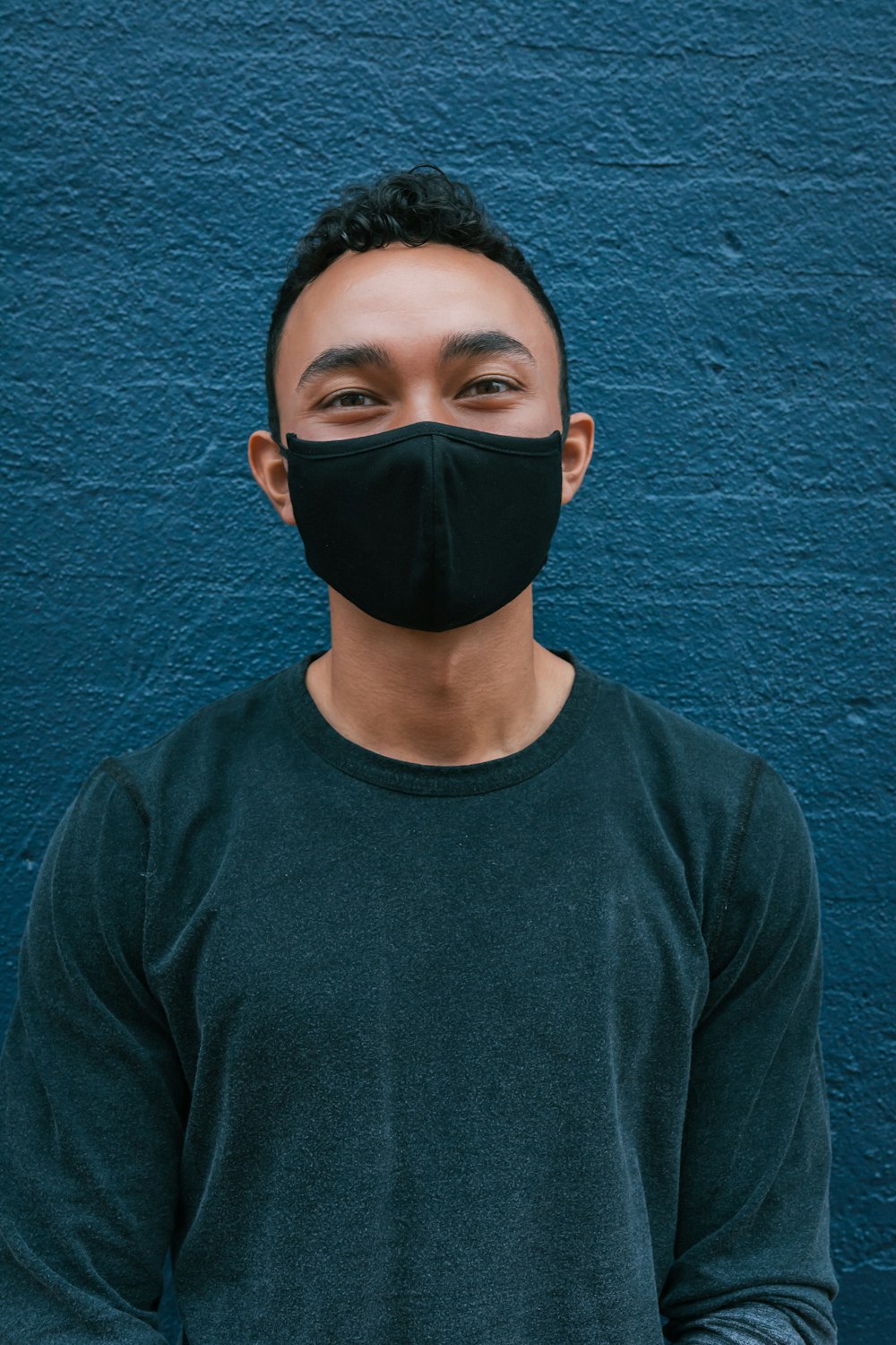 Homme en chemise bleue à col rond portant un masque noir