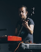 Carlos playing guitar with intense focus under stage lights.