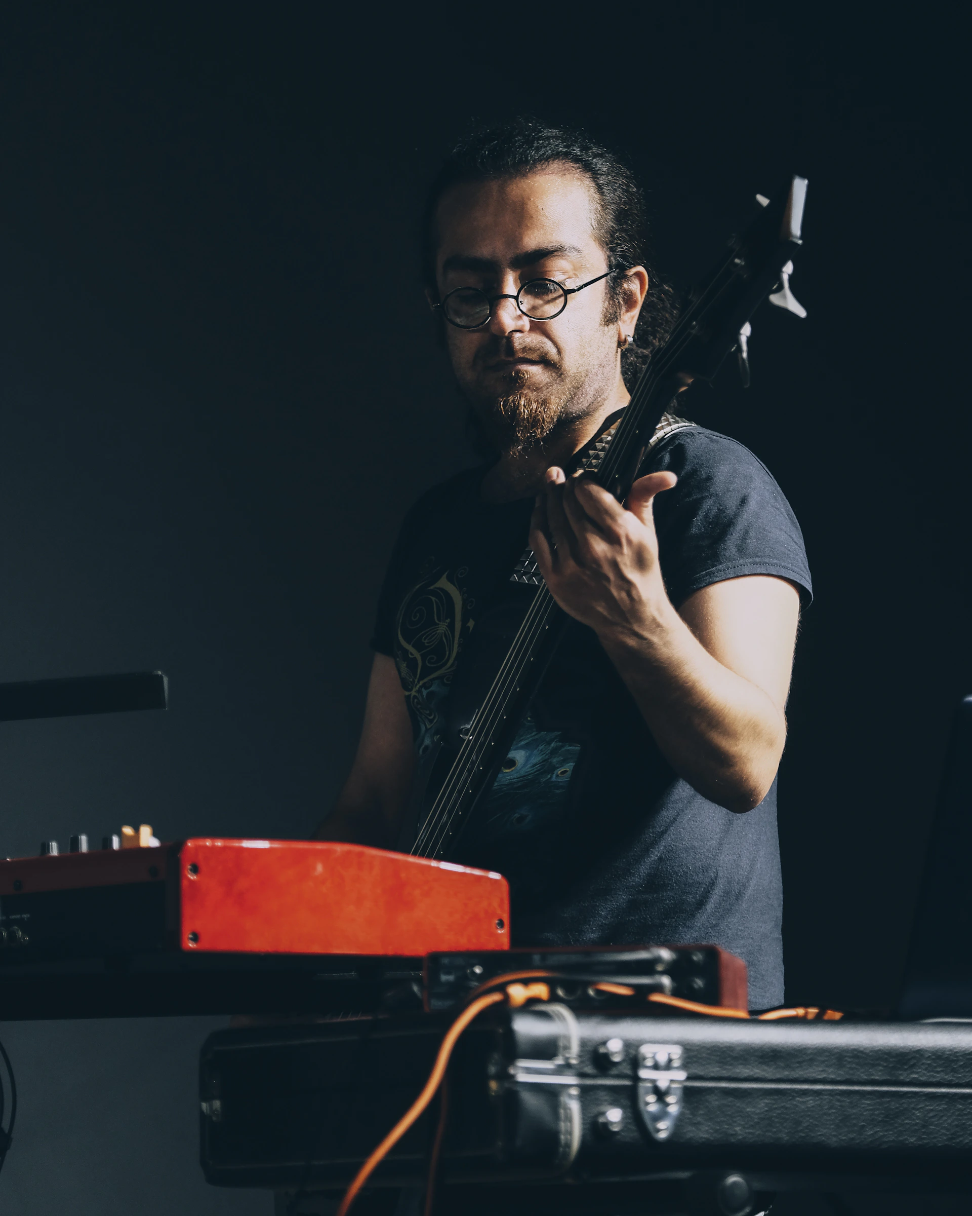 An intimate shot of a musician passionately playing guitar in the dimly lit Alchemy Records studio, surrounded by modern mixing equipment.