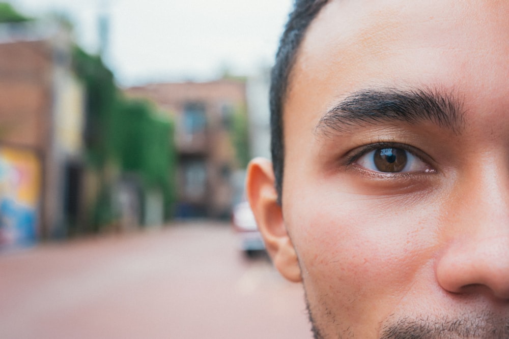 mans face near green and brown concrete building during daytime