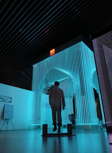 man in black jacket standing on blue lighted room