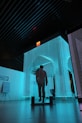 man in black jacket standing on blue lighted room