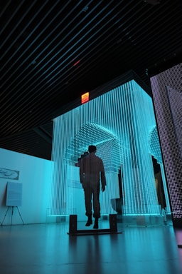 man in black jacket standing on blue lighted room