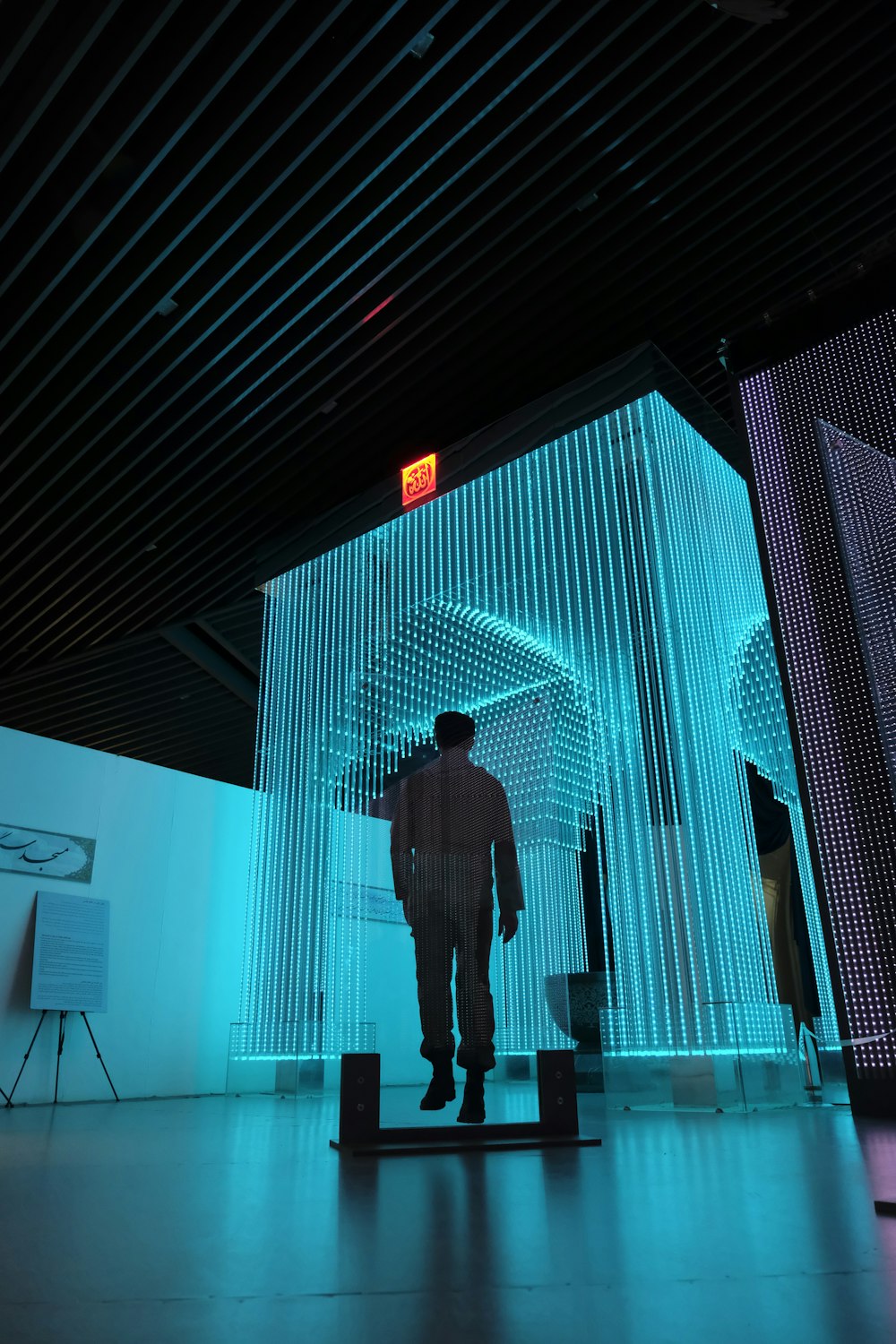 man in black jacket standing on blue lighted room