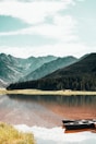lake near green trees and mountain under blue sky during daytime