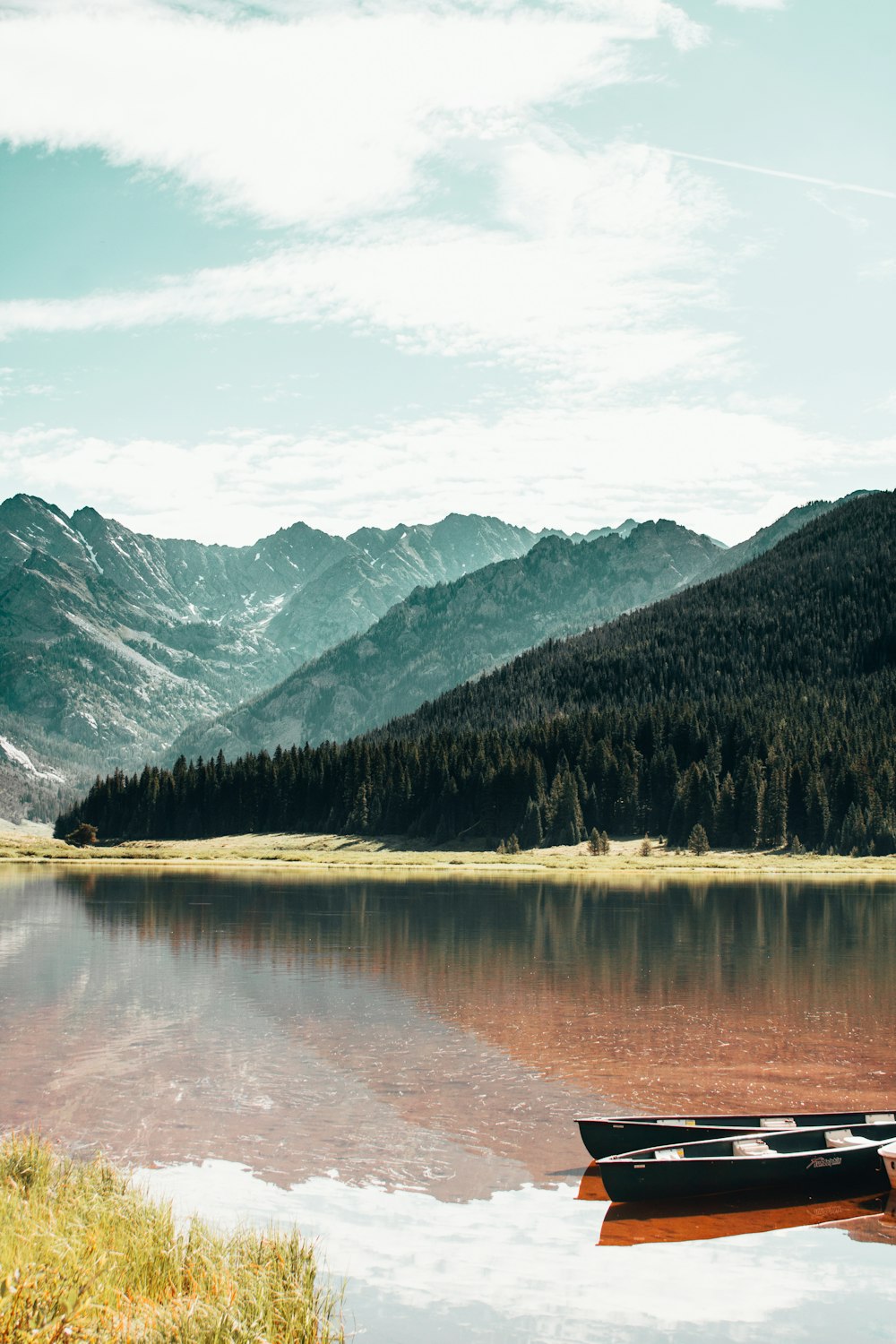 lake near green trees and mountain under blue sky during daytime