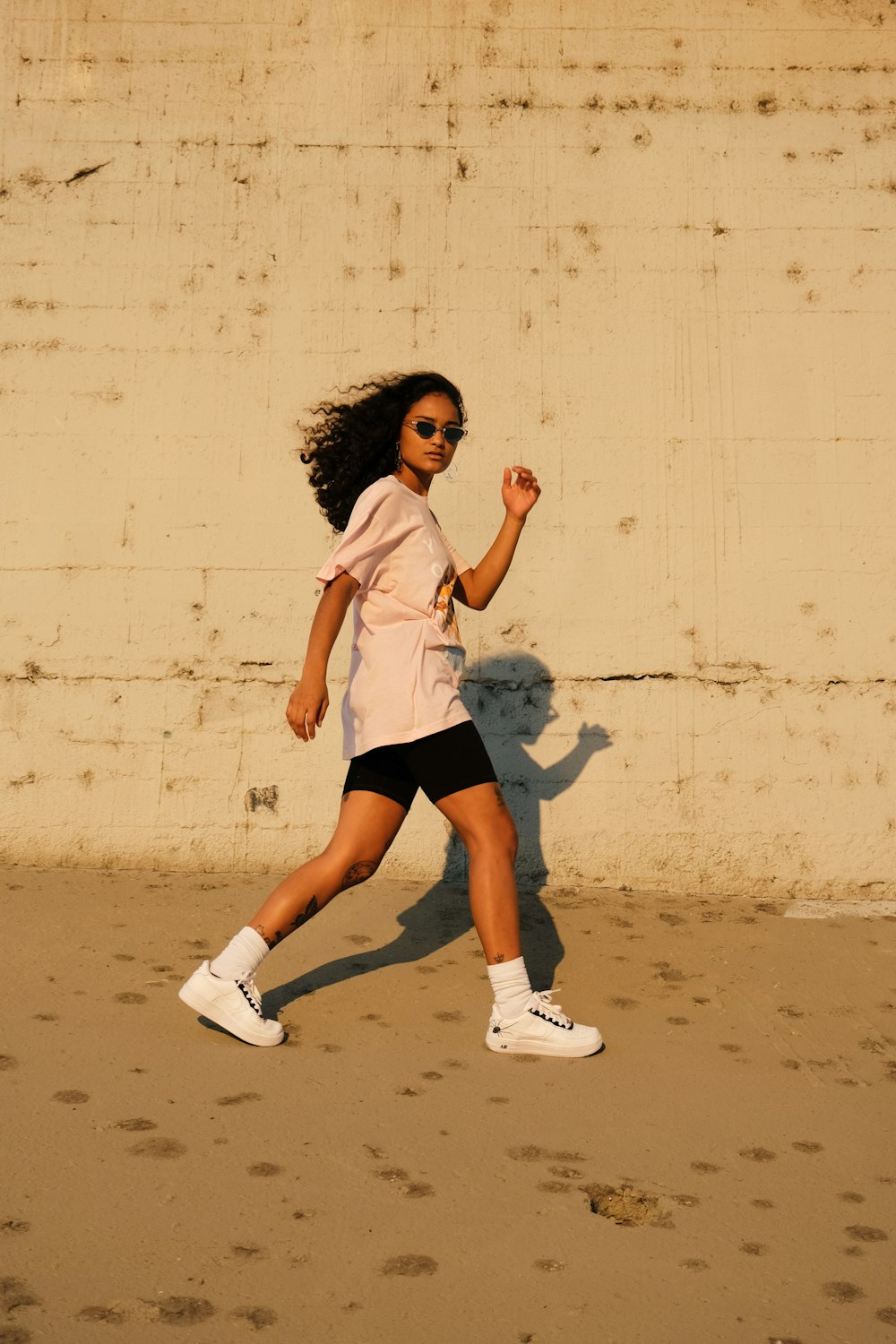 woman in white shirt and black shorts standing beside white wall