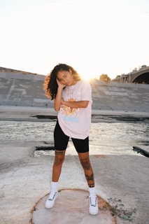 woman in pink t-shirt and black shorts standing on beach during daytime