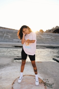 woman in pink t-shirt and black shorts standing on beach during daytime