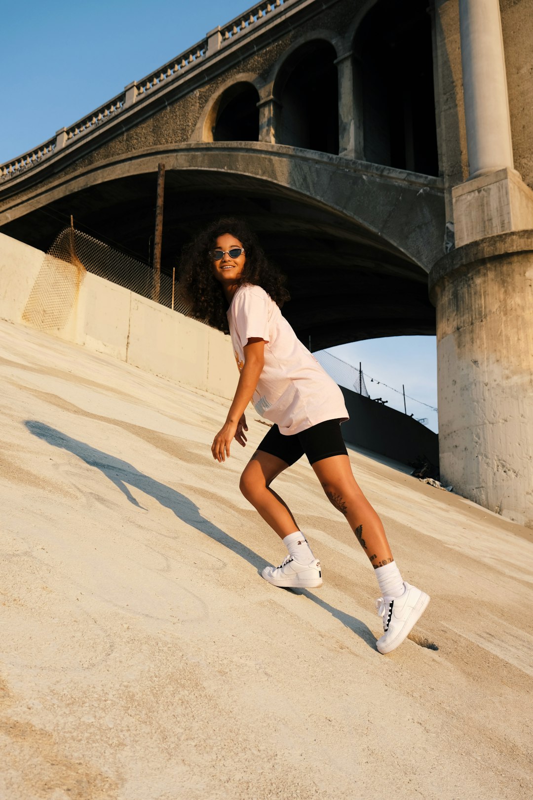 woman in white t-shirt and black shorts standing on brown sand during daytime