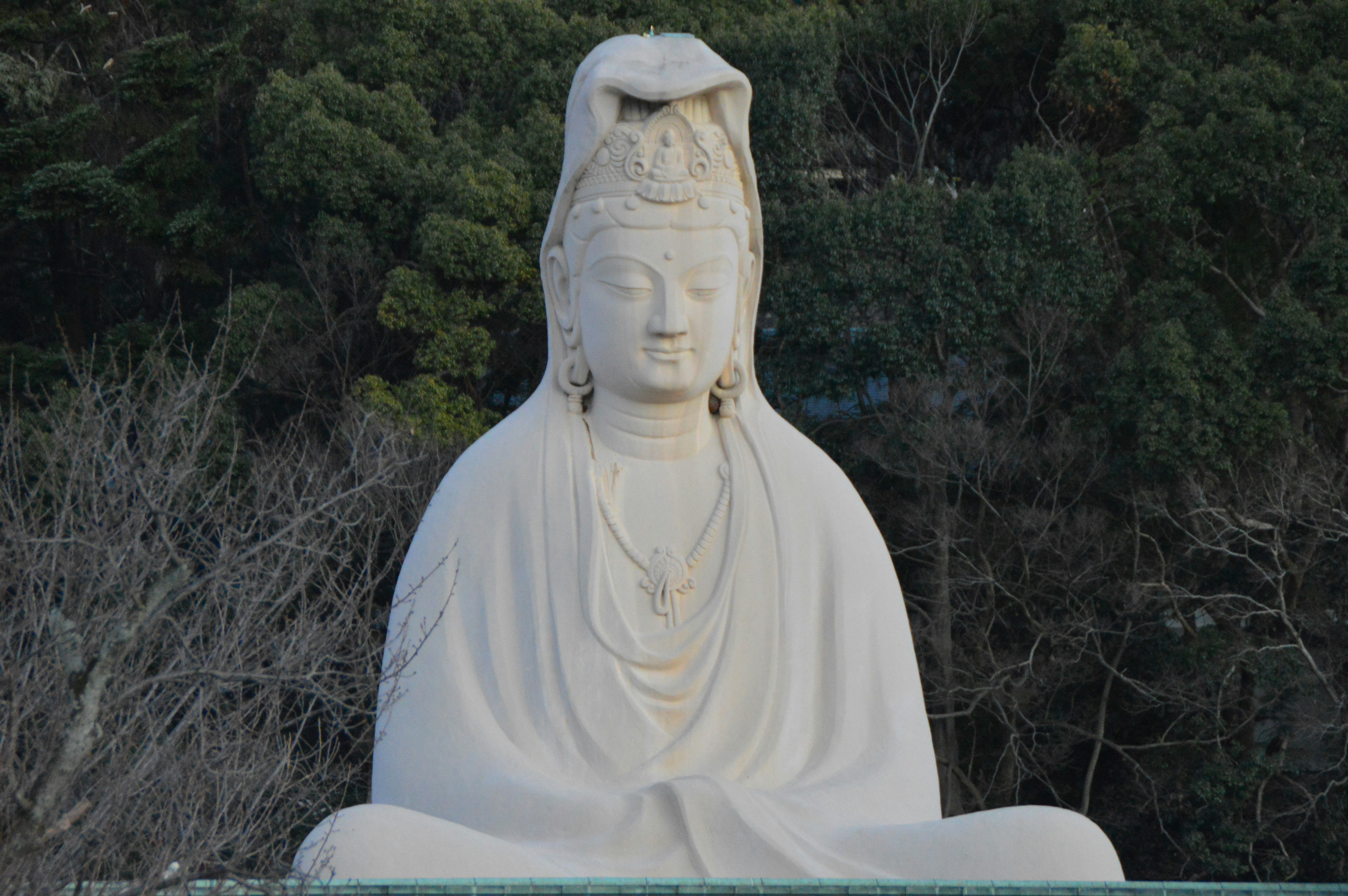 white concrete statue near green trees during daytime
