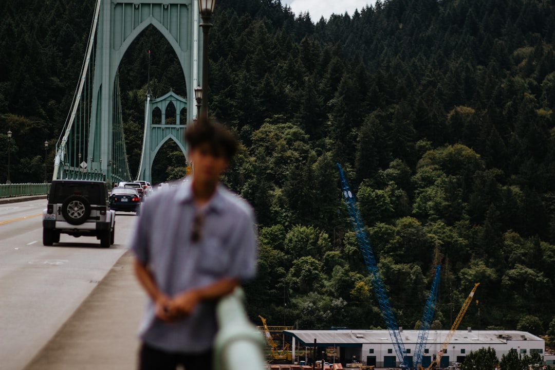 man in white shirt standing near bridge during daytime