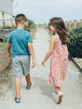 man in blue crew neck t-shirt and woman in red and white floral dress walking