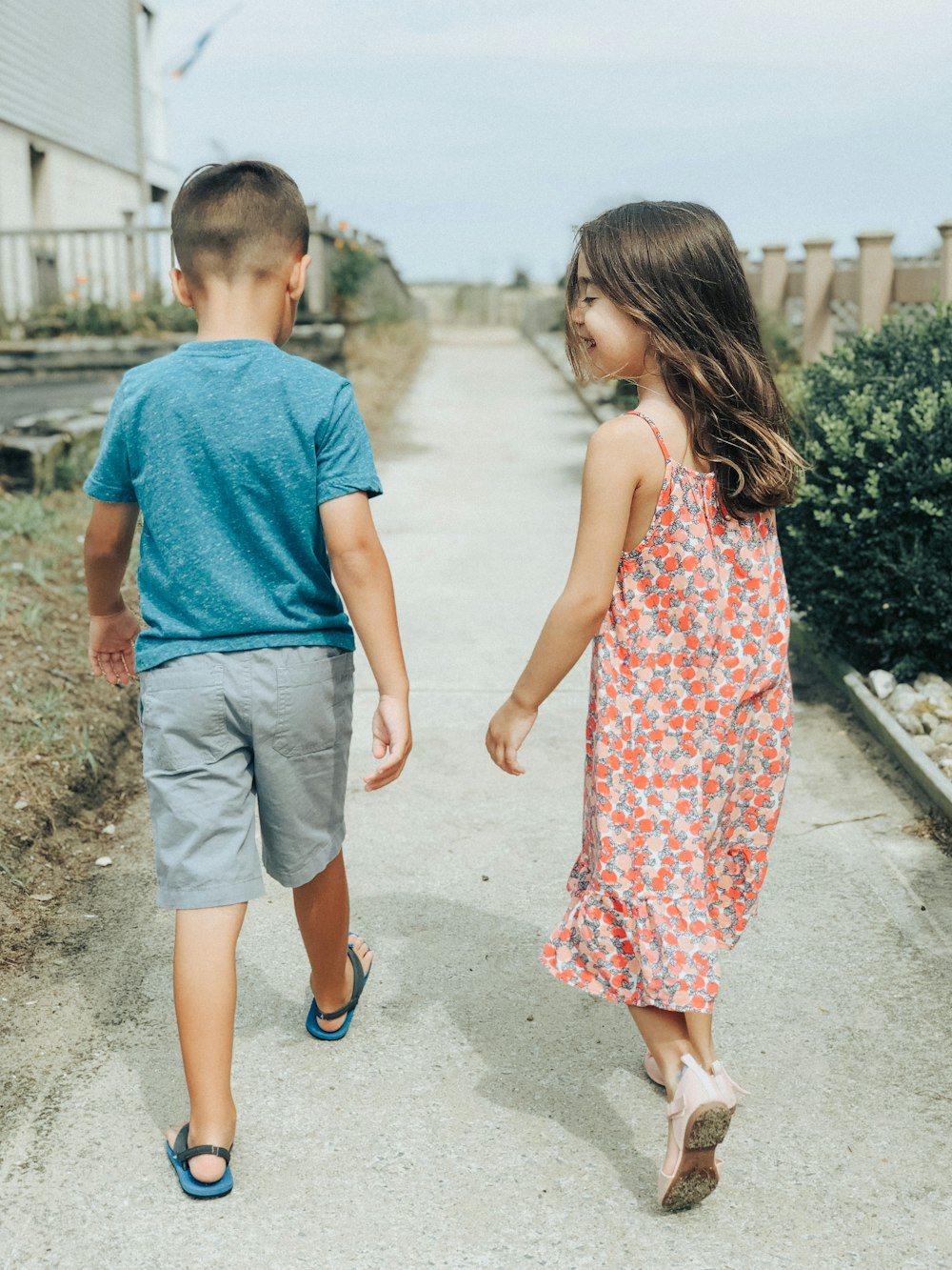 homme en t-shirt à col rond bleu et femme en robe à fleurs rouge et blanche marchant