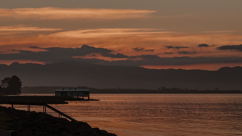 silhouette of dock on sea during sunset