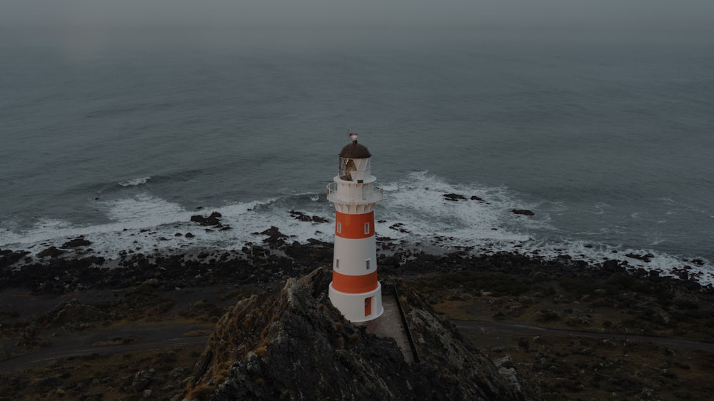 white and red lighthouse near body of water during daytime