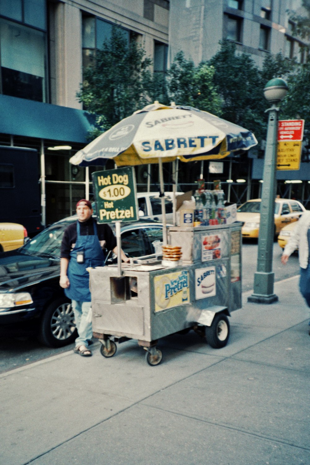 man in blue t-shirt and blue denim jeans standing beside food cart