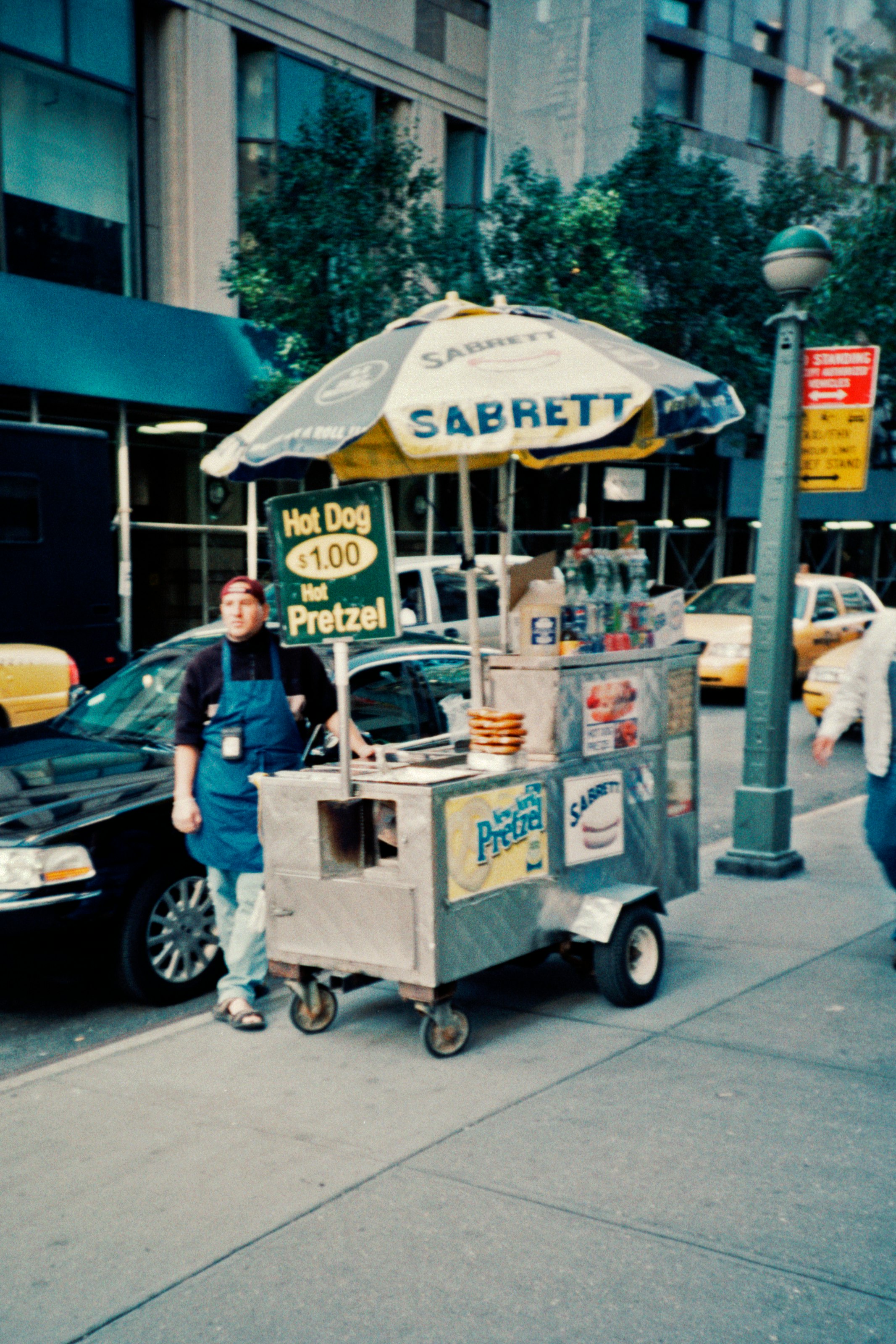man in blue t-shirt and blue denim jeans standing beside food cart