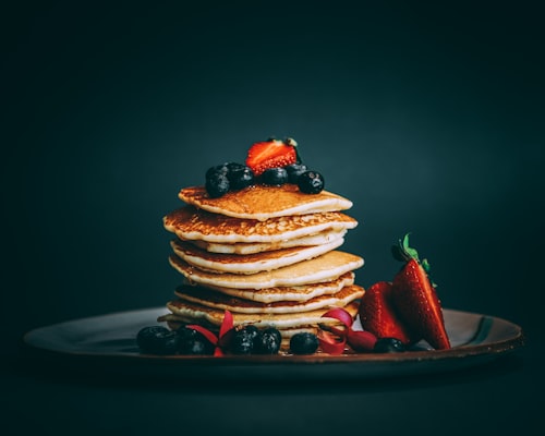 A stack of flapjacks with fruit on top.