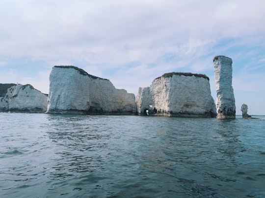 brown rock formation on sea under white clouds during daytime in Purbeck Heritage Coast United Kingdom