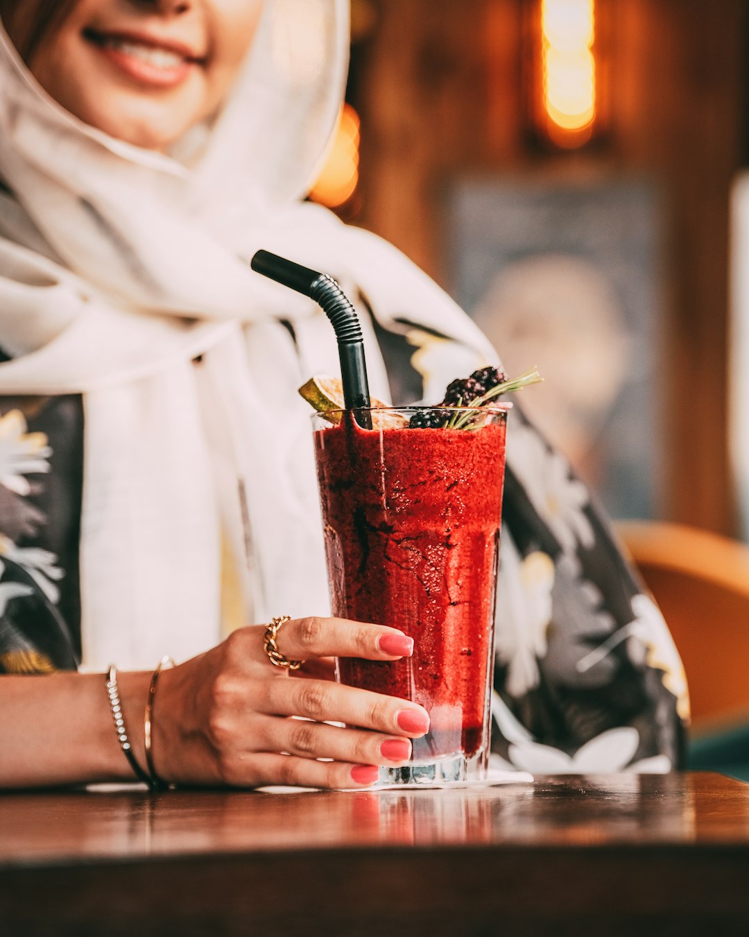 person in white robe holding clear drinking glass with red liquid