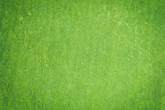 Aerial view of a large commercial artificial grass installation in progress with workers and machinery.